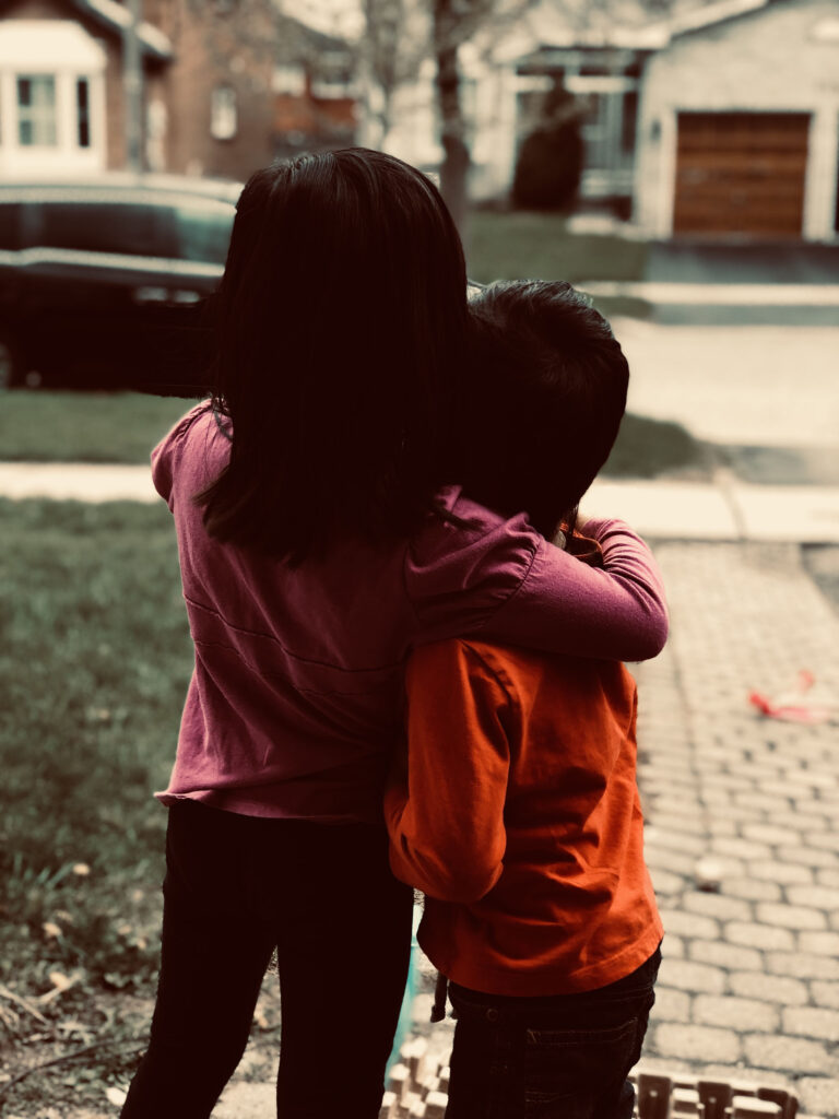 siblings bond in embrace while looking out into the distance
